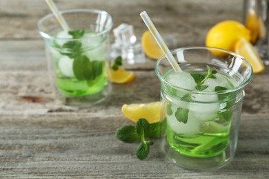 Delicious cocktail with mint and ice balls on wooden table, space for text