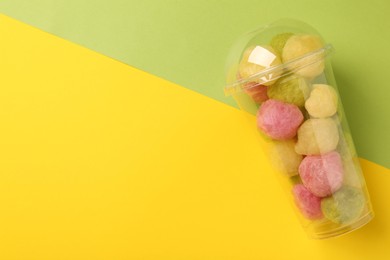 Photo of Plastic cup with delicious cotton balls on color background, top view and space for text. Sweet candy
