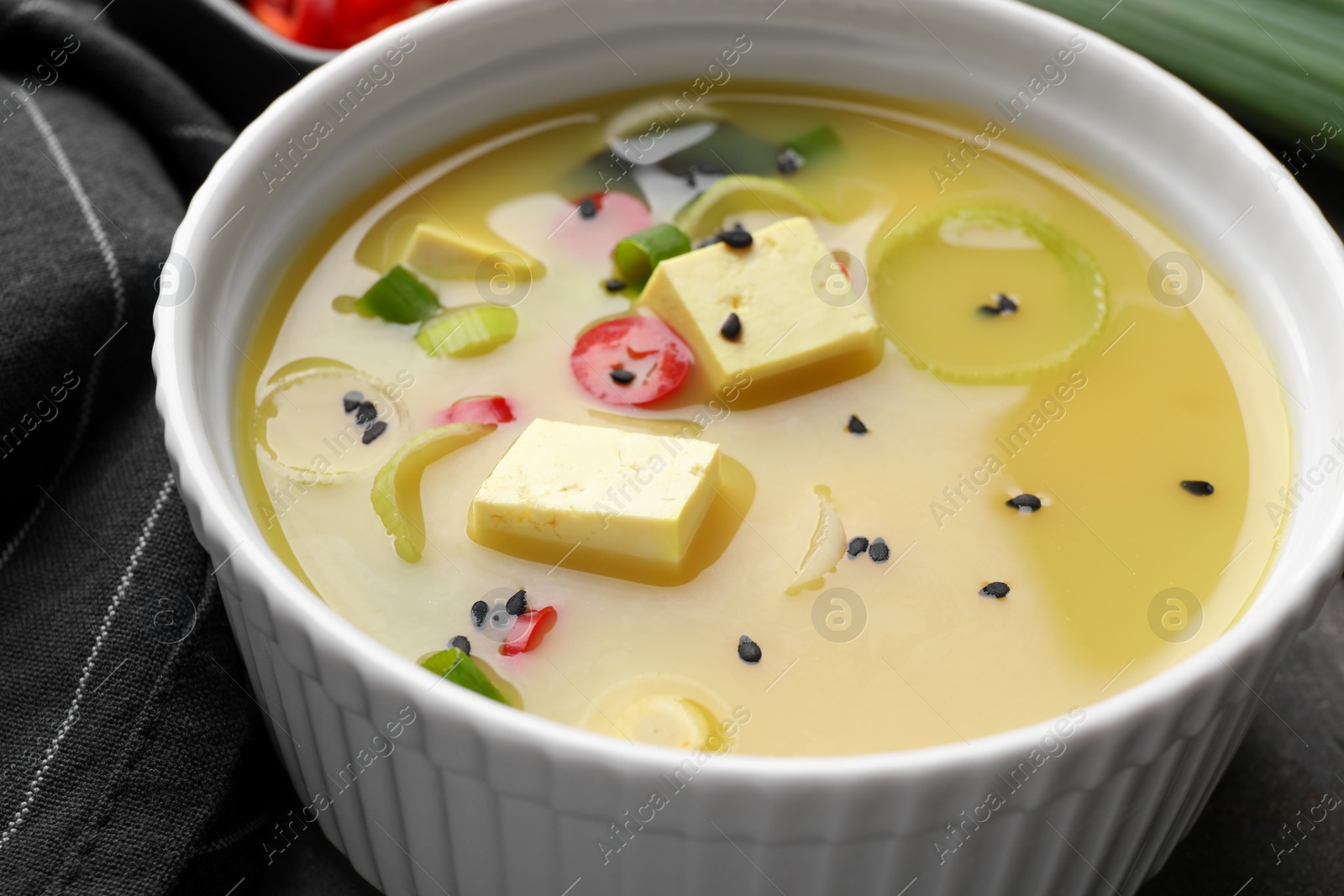 Photo of Bowl of delicious miso soup with tofu on table, closeup