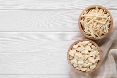 Photo of Bowls with cut parsnip on white wooden table, flat lay. Space for text
