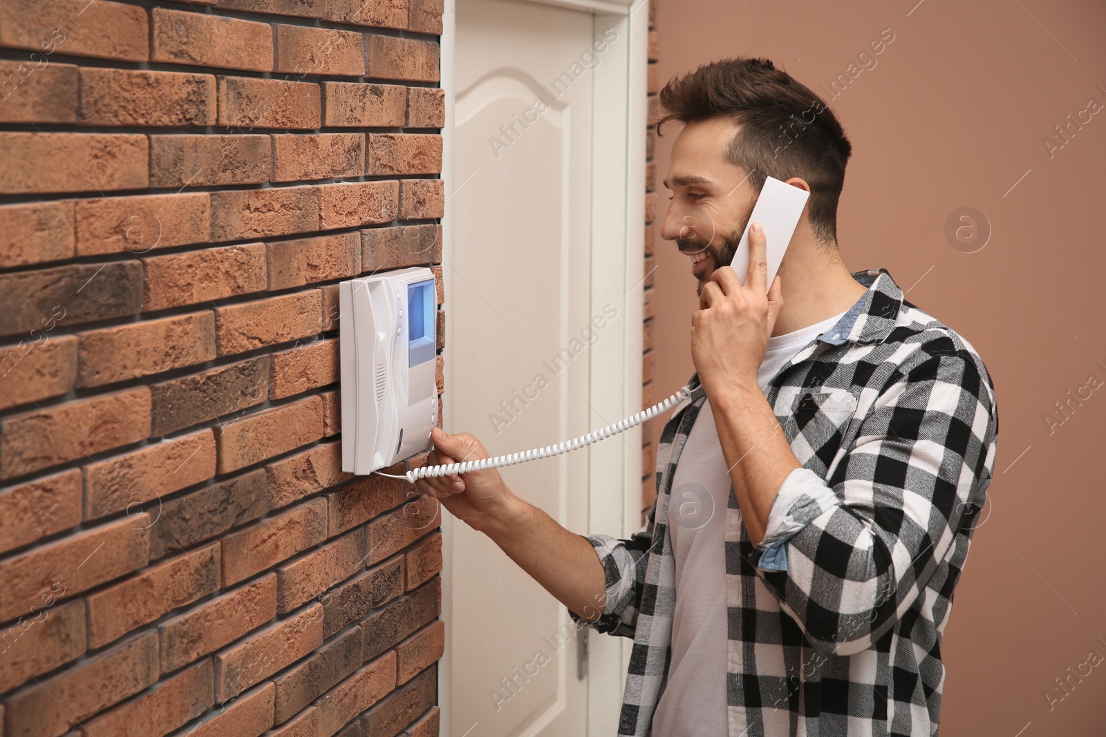 Photo of Man with handset answering intercom call indoors