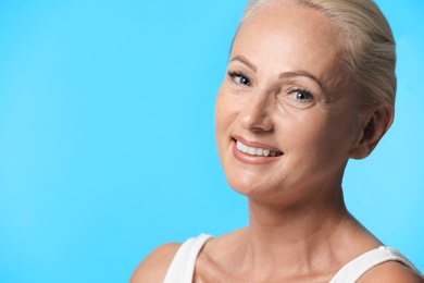 Photo of Portrait of beautiful mature woman with perfect skin on light blue background. Space for text