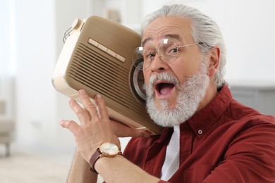Senior man with retro radio receiver at home