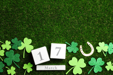 Photo of Flat lay composition with horseshoe and block calendar on grass, space for text. St. Patrick's Day celebration