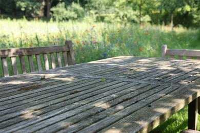 Empty wooden table with bench on sunny day in garden