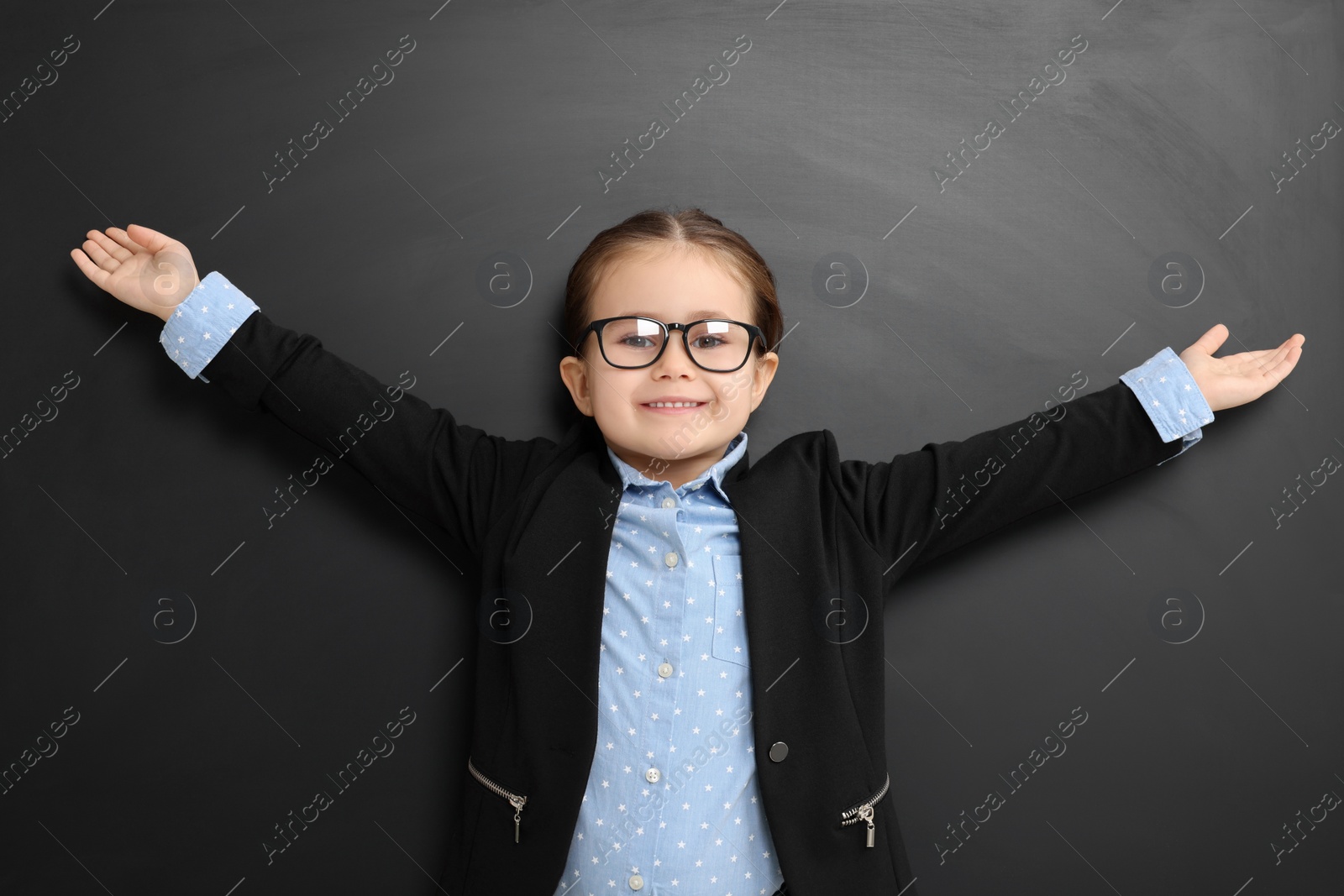 Photo of Happy little school child in uniform near chalkboard