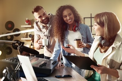 Photo of People working in modern radio studio with professional equipment