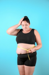 Photo of Fat woman with measuring tape on color background. Weight loss