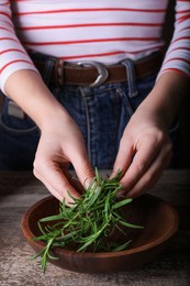 Photo of Woman with green rosemary sprigs at wooden table, closeup