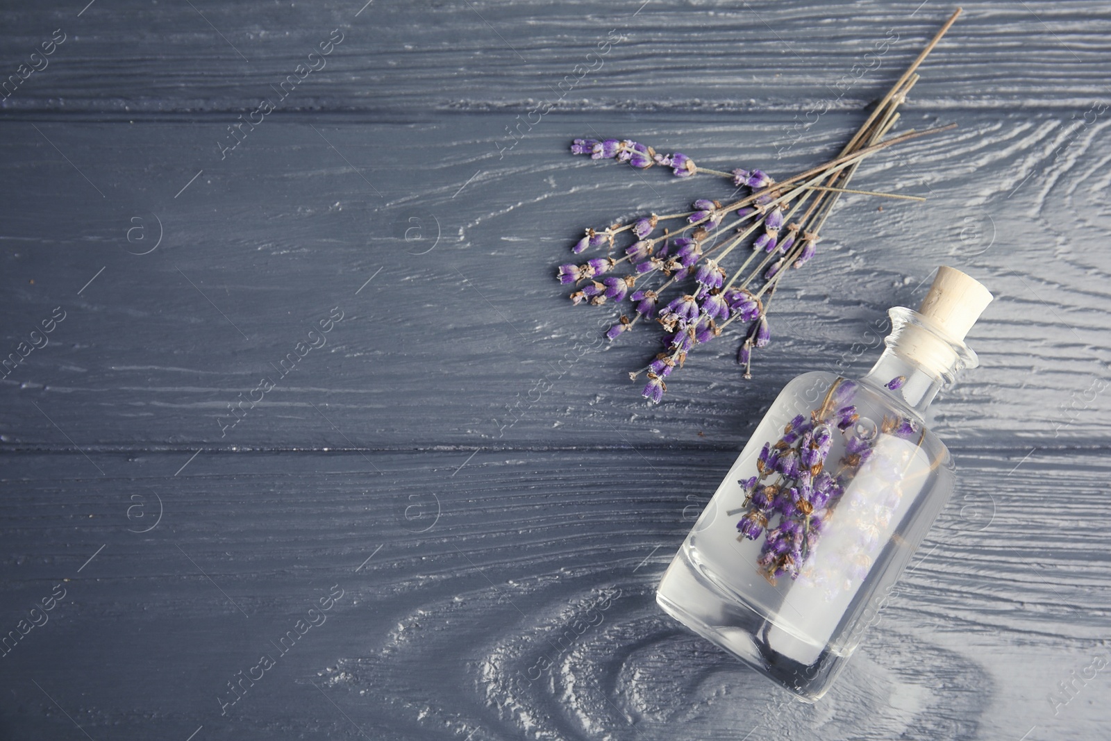 Photo of Flat lay composition with natural herbal oil and lavender flowers on wooden background. Space for text