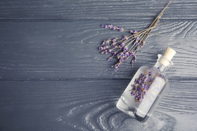 Photo of Flat lay composition with natural herbal oil and lavender flowers on wooden background. Space for text