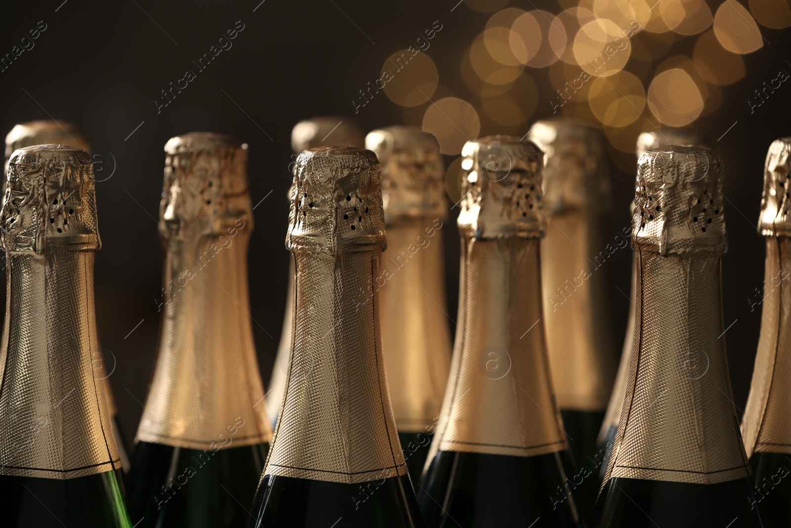 Photo of Many bottles of champagne on blurred background, closeup