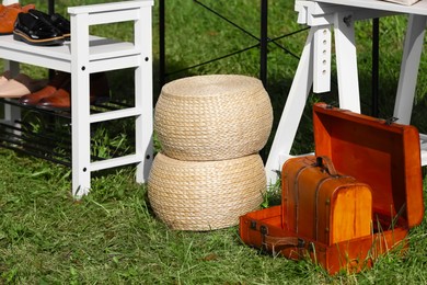 Photo of Wicker baskets and suitcases on grass near shoe rack outdoors. Garage sale