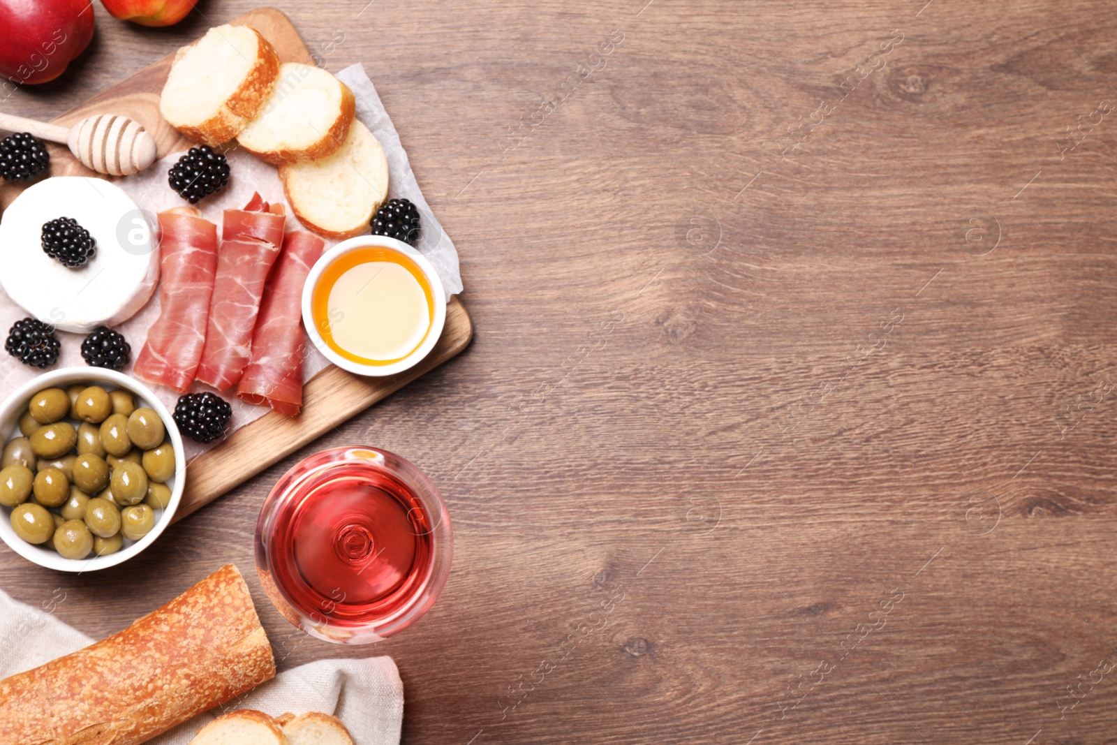 Photo of Glass of delicious rose wine and snacks on wooden table, flat lay. Space for text