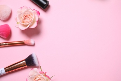 Photo of Flat lay composition with makeup brushes and roses on pink background. Space for text