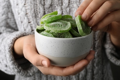 Photo of Woman holding bowl with slices of tasty kiwi, closeup. Dried fruit as healthy food