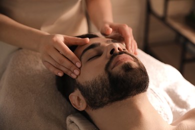 Young man receiving facial massage in beauty salon