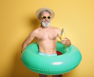 Photo of Shirtless man with inflatable ring and glass of cocktail on color background