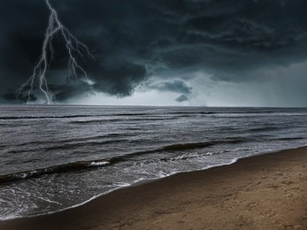 Image of Dark cloudy sky with lightnings over beach and sea. Thunderstorm