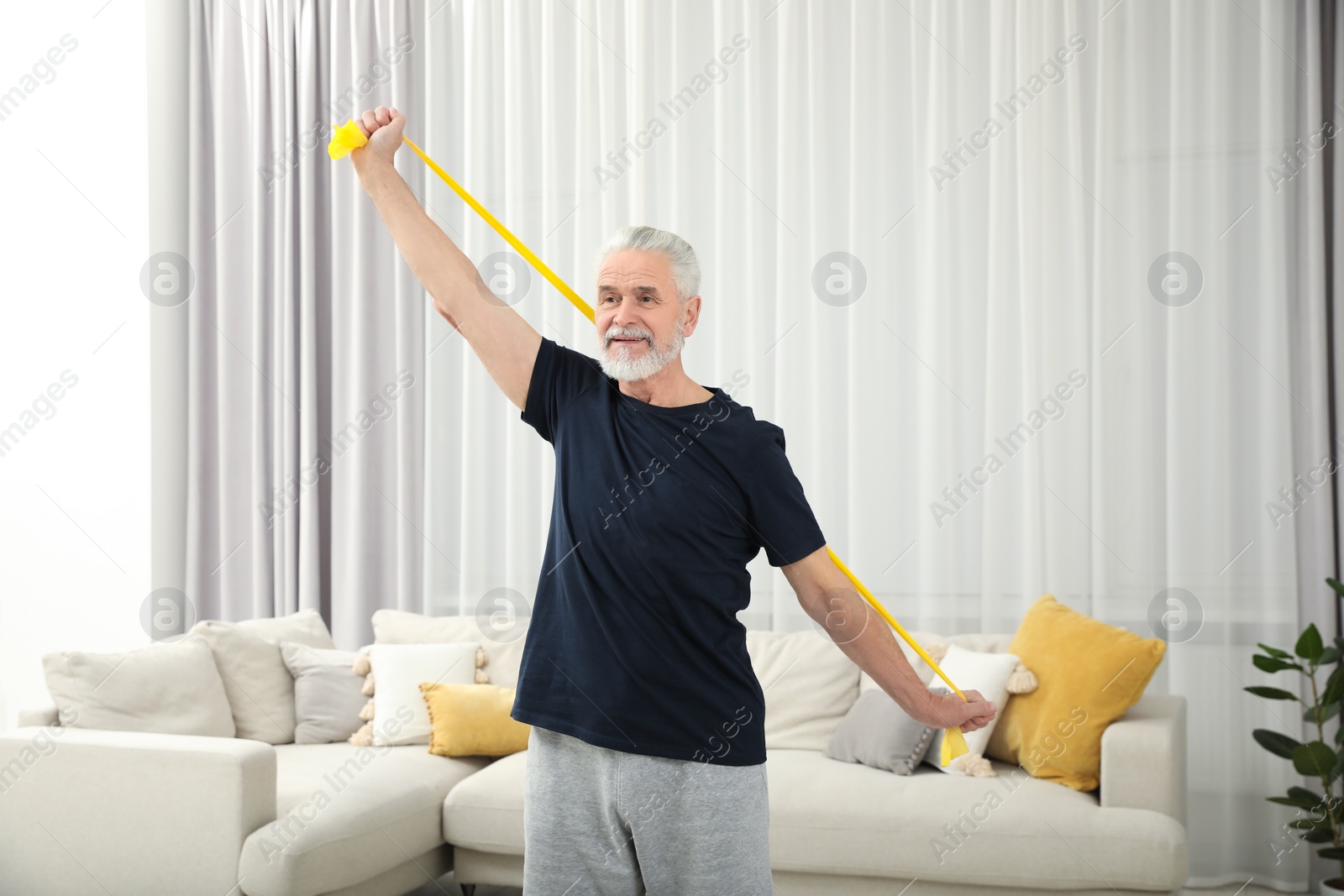 Photo of Senior man doing exercise with fitness elastic band at home