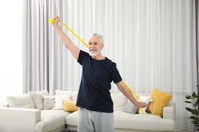 Senior man doing exercise with fitness elastic band at home