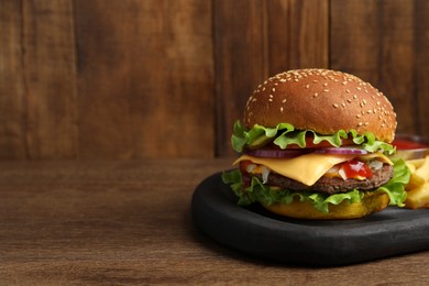 Photo of Delicious burger with beef patty and french fries on wooden table, space for text