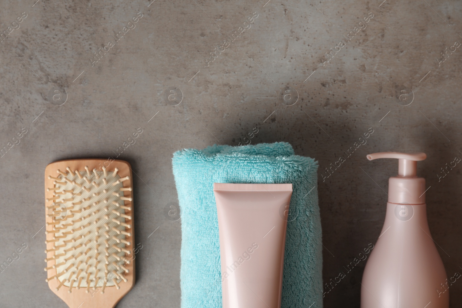 Photo of Different hair products, towel and brush on grey table, flat lay. Space for text