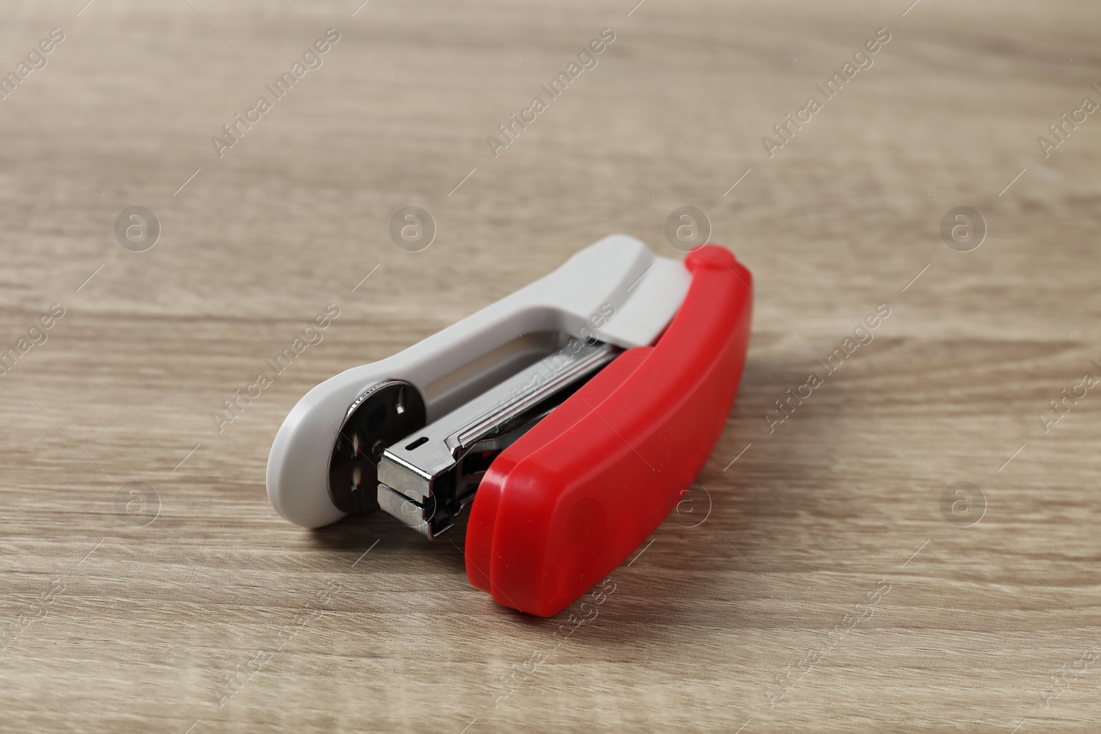 Photo of One bright stapler on wooden table, closeup