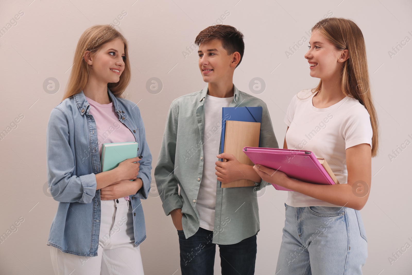 Photo of Group of teenage students with stationery on beige background