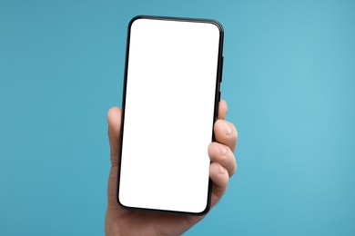 Photo of Man showing smartphone on light blue background, closeup. Mockup for design