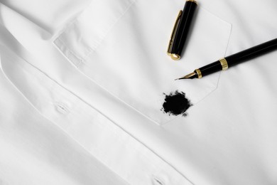 Photo of Pen and stain of black ink on white shirt. Space for text