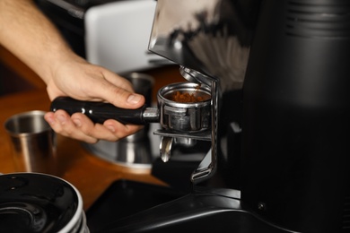 Photo of Barista pouring milled coffee from grinding machine into portafilter, closeup