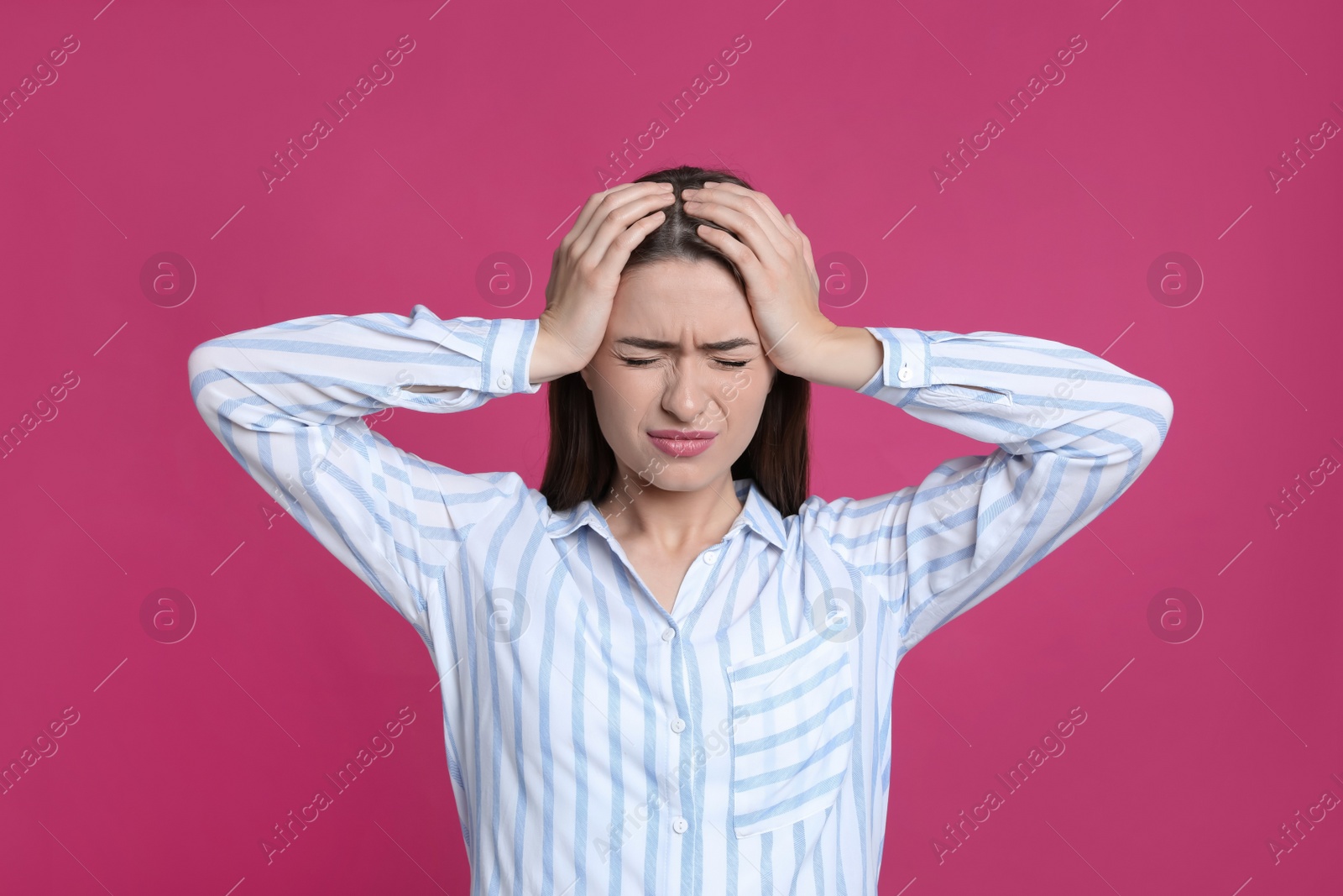 Photo of Young woman suffering from headache on pink background