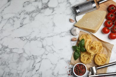 Flat lay composition with cooking utensils and fresh ingredients on white marble table. Space for text