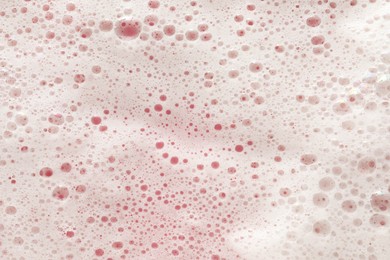 White washing foam on pale pink background, top view