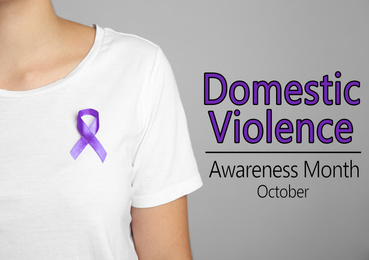 Image of Woman with purple ribbon on grey background, closeup. Symbol of Domestic Violence Awareness