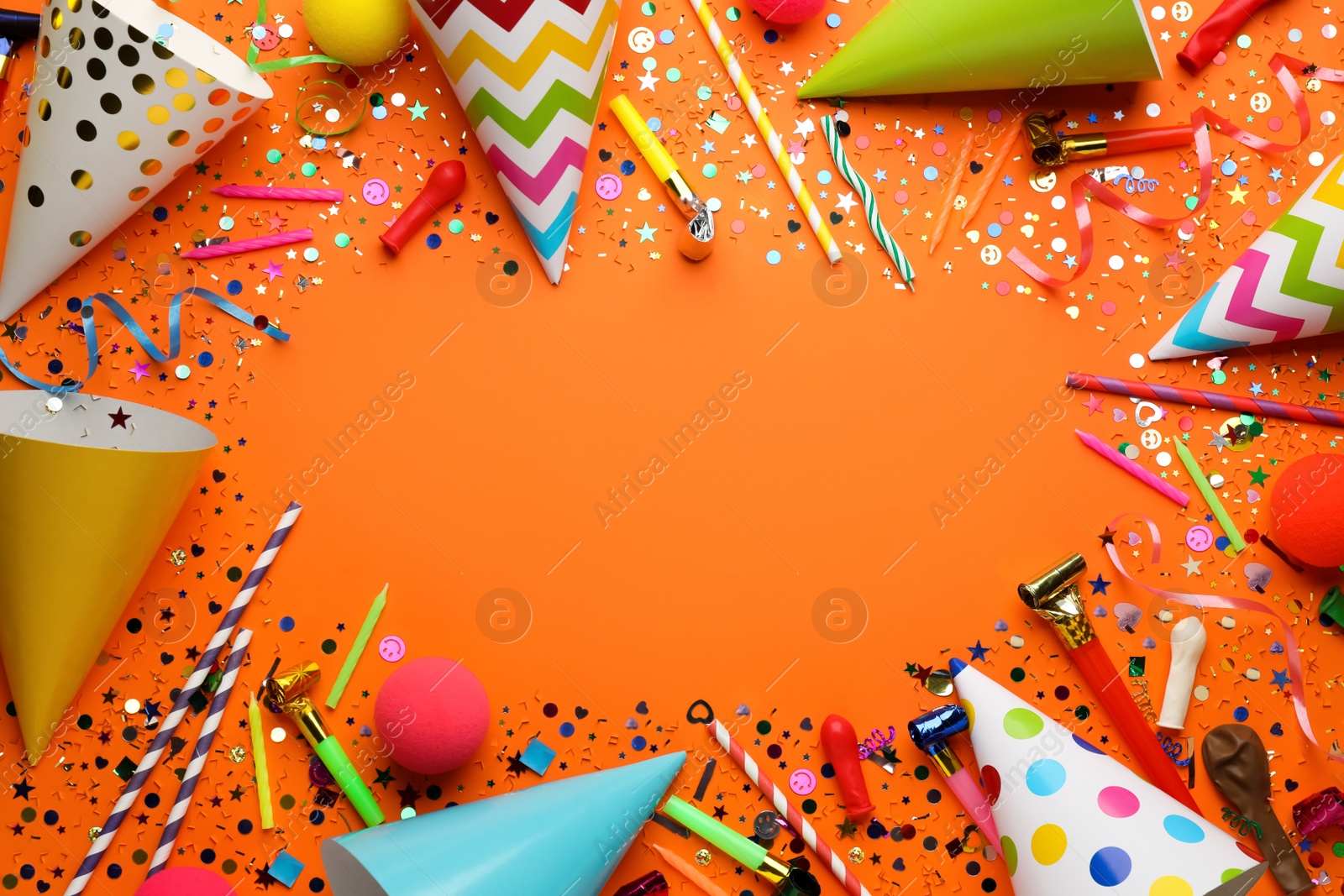 Photo of Frame of festive items on orange background, flat lay with space for text. Surprise party concept