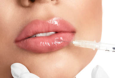 Photo of Young woman getting lips injection on white background, closeup