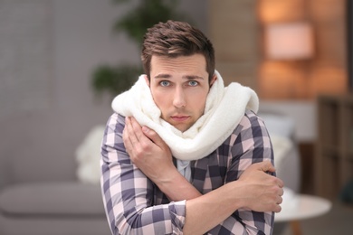 Photo of Sad young man suffering from cold on blurred background