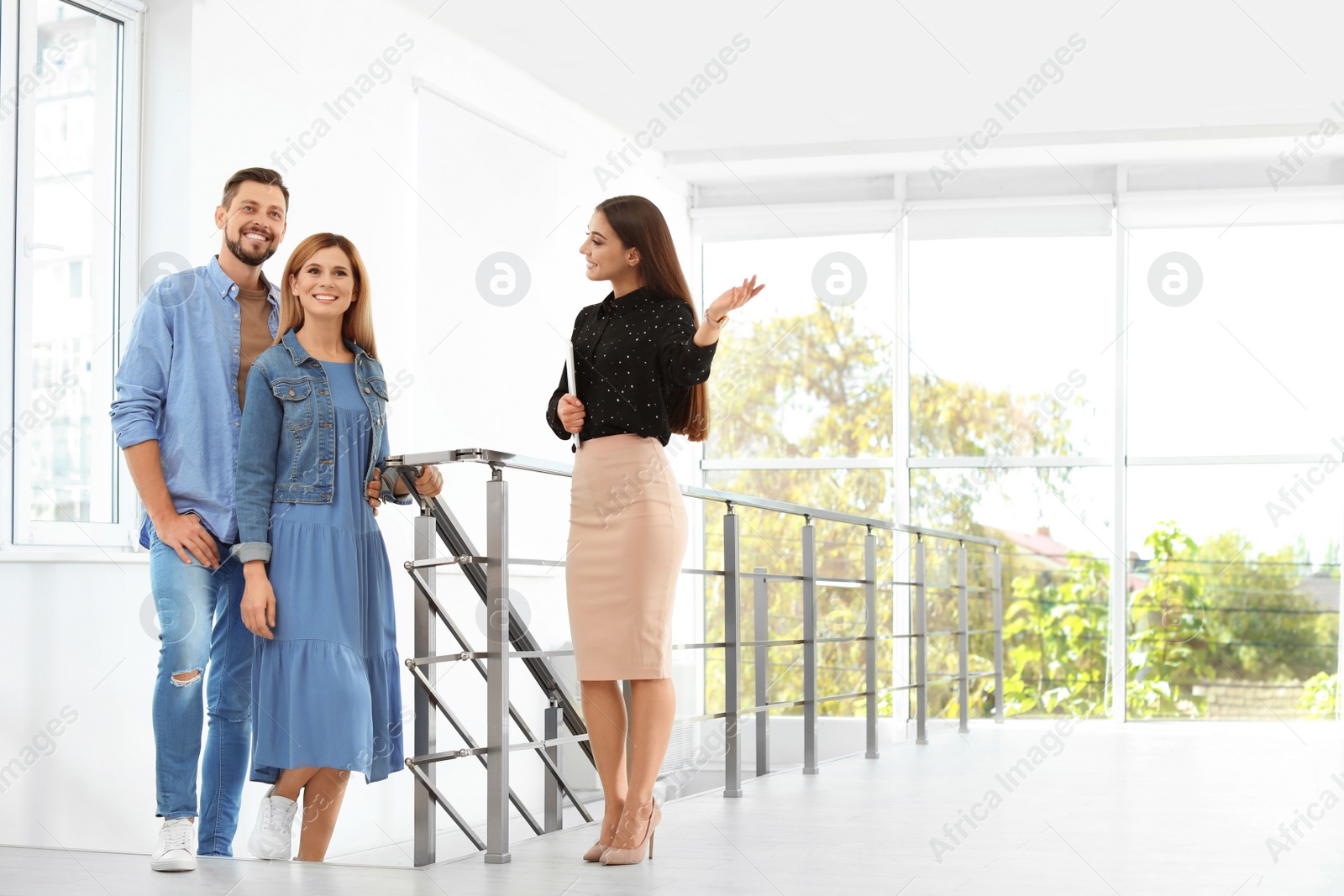 Photo of Female real estate agent showing new house to couple, indoors