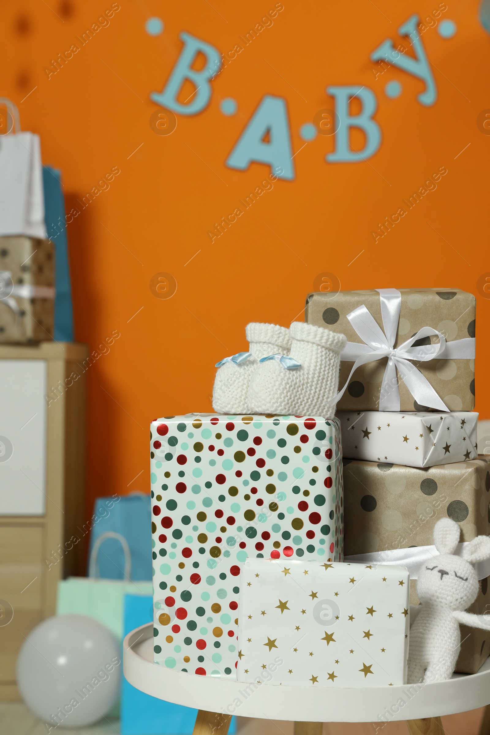 Photo of Baby shower party. Festive decor, gift boxes, booties and toy in stylish room