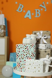 Baby shower party. Festive decor, gift boxes, booties and toy in stylish room