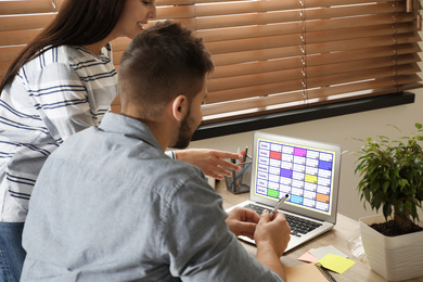 Photo of Colleagues working with calendar app on laptop in office