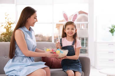 Photo of Mother and daughter holding basket with Easter eggs at home