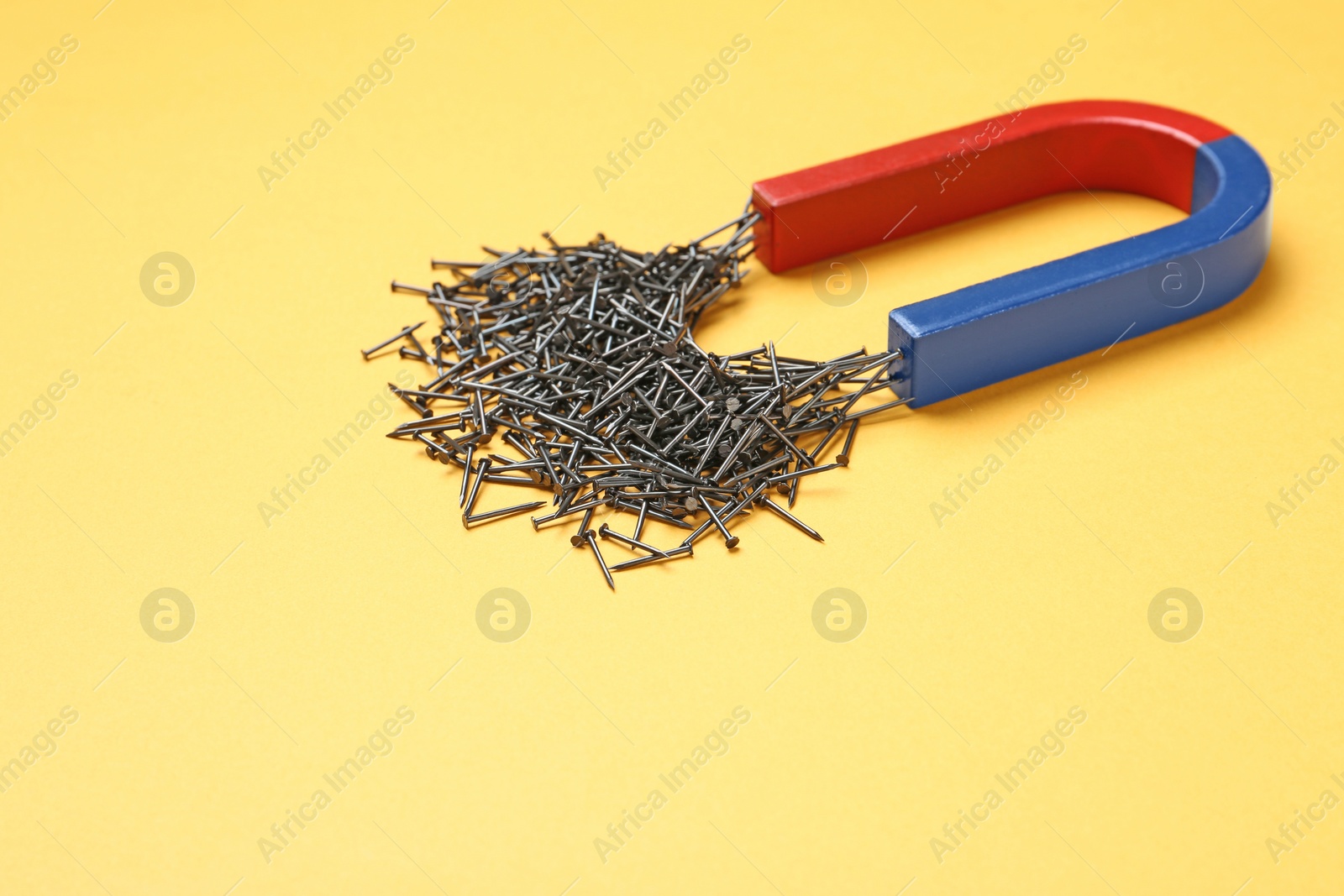 Photo of Magnet attracting nails on color background, space for text