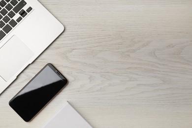 Photo of Laptop and smartphone on wooden table flat lay. Space for text