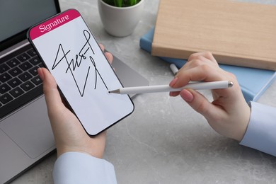 Electronic signature. Woman using stylus and mobile phone at table, closeup