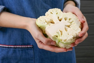 Photo of Woman holding fresh cauliflower against dark background, closeup