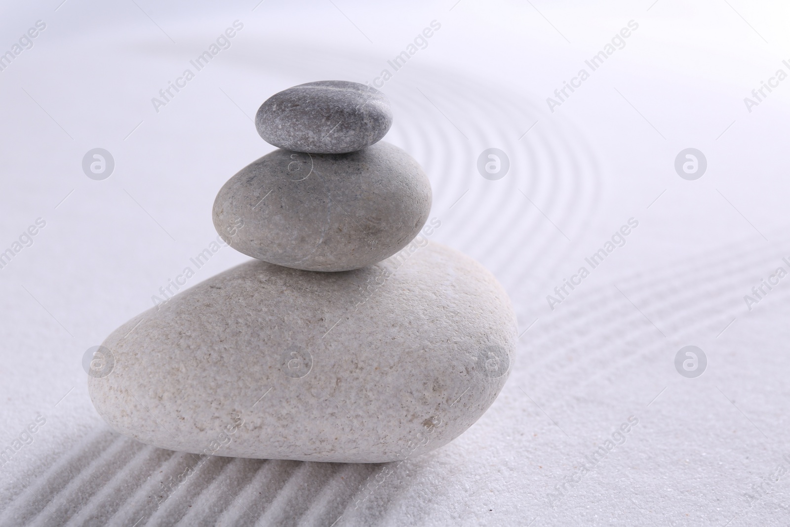 Photo of Zen garden stones on white sand with pattern, closeup