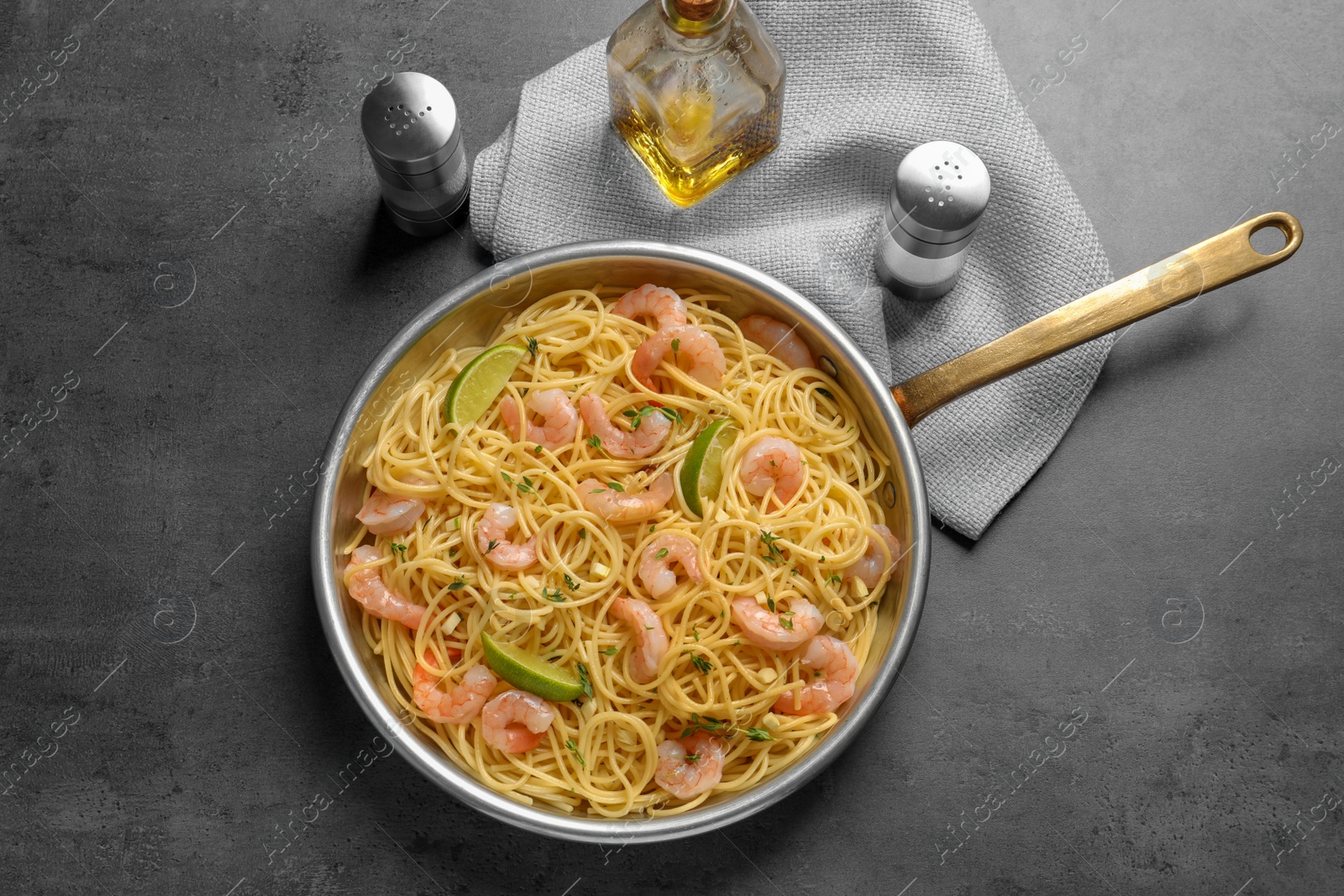 Photo of Frying pan with spaghetti and shrimps on grey background, top view